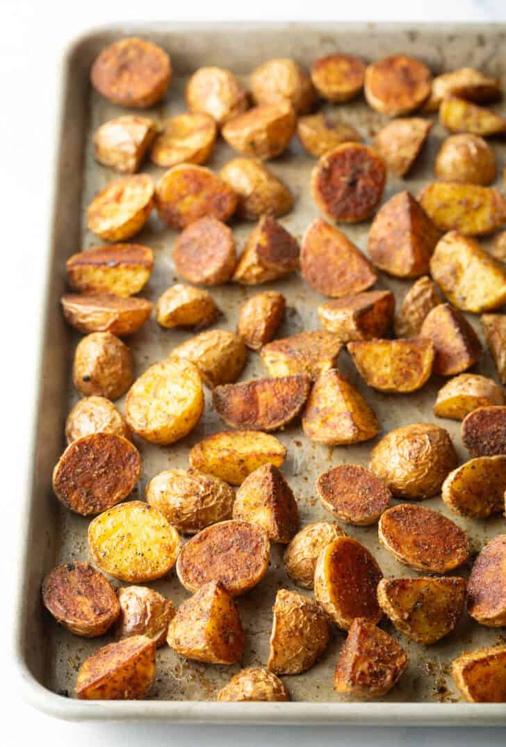 Halved yellow baby potatoes roasted on a baking sheet.