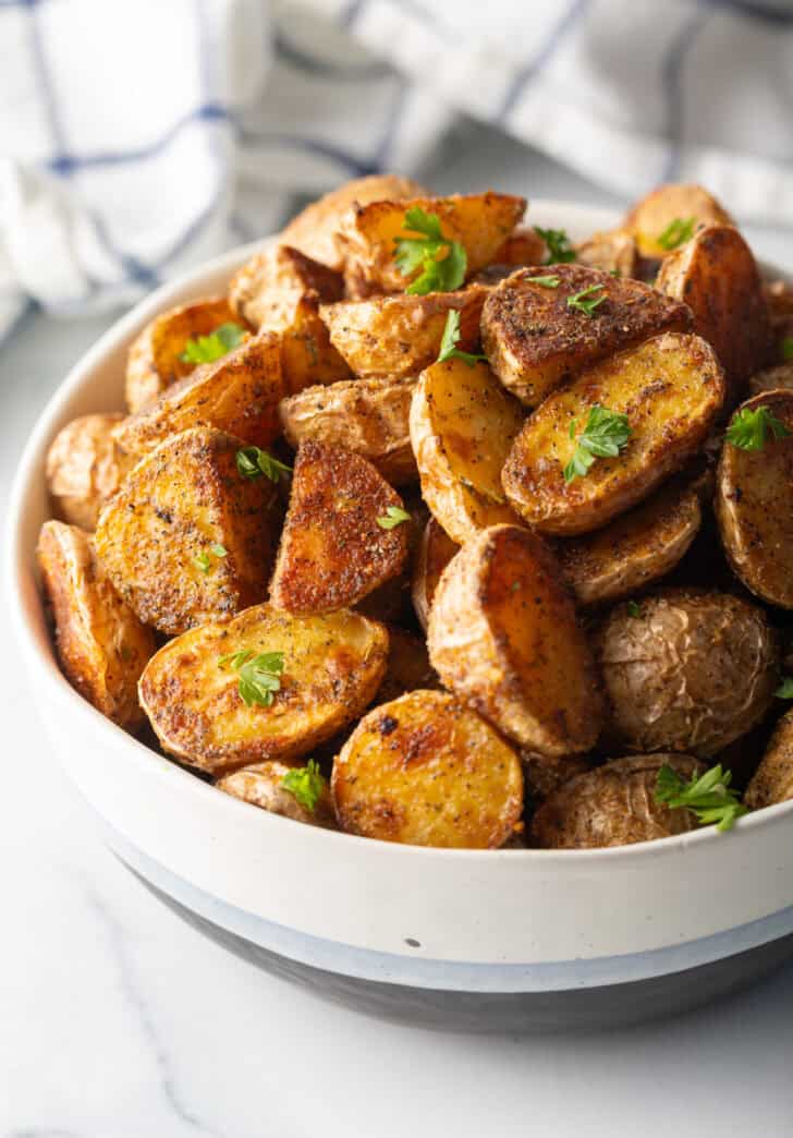 Bowl of crispy oven roasted potatoes sprinkled with fresh parsley.