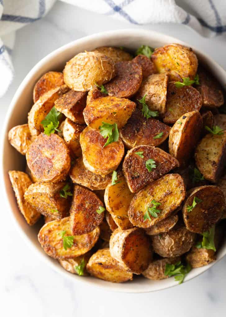 Bowl of crispy oven roasted potatoes sprinkled with fresh parsley.