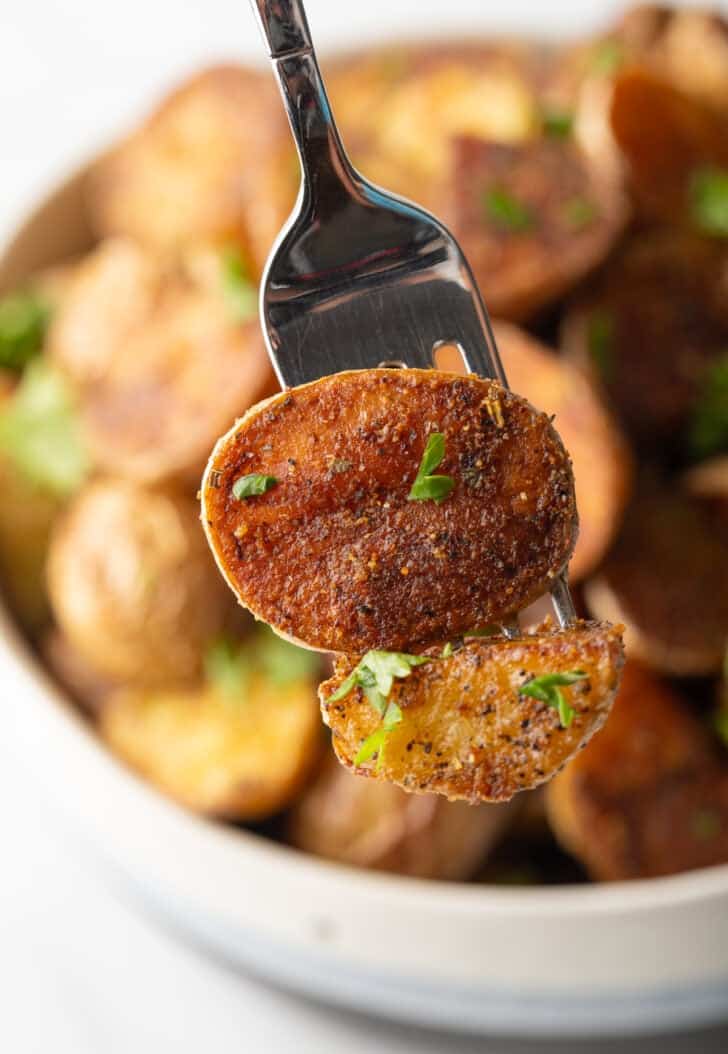 Fork showing a crispy potato piece to camera.