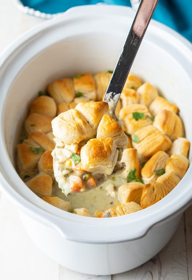 Spoon with a serving of crockpot chicken pot pie on it with more in the background. 