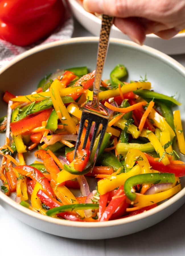 Fork taking a bite of sliced peppers from a bowl.