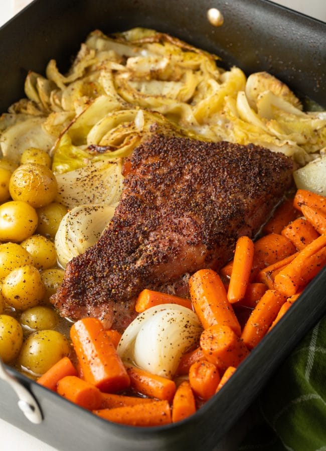 Corned beef, cabbage, potatoes, carrots and onions all roasted in a roasting pan. 
