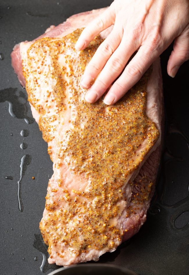 Hand seasoning corned beef brisket with a mustard seasoning. 