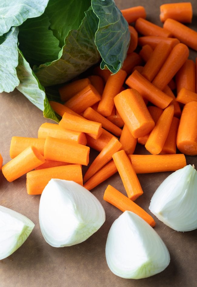 Freen cabbage, carrots, onion on cutting board.