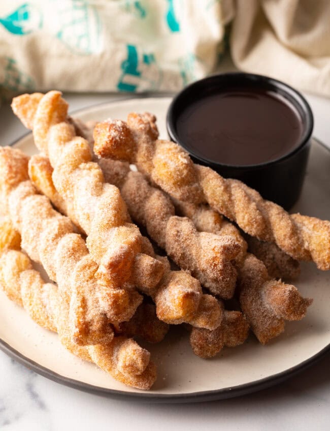 cinnamon twist recipe stacked, with bowl of chocolate sauce on the side.