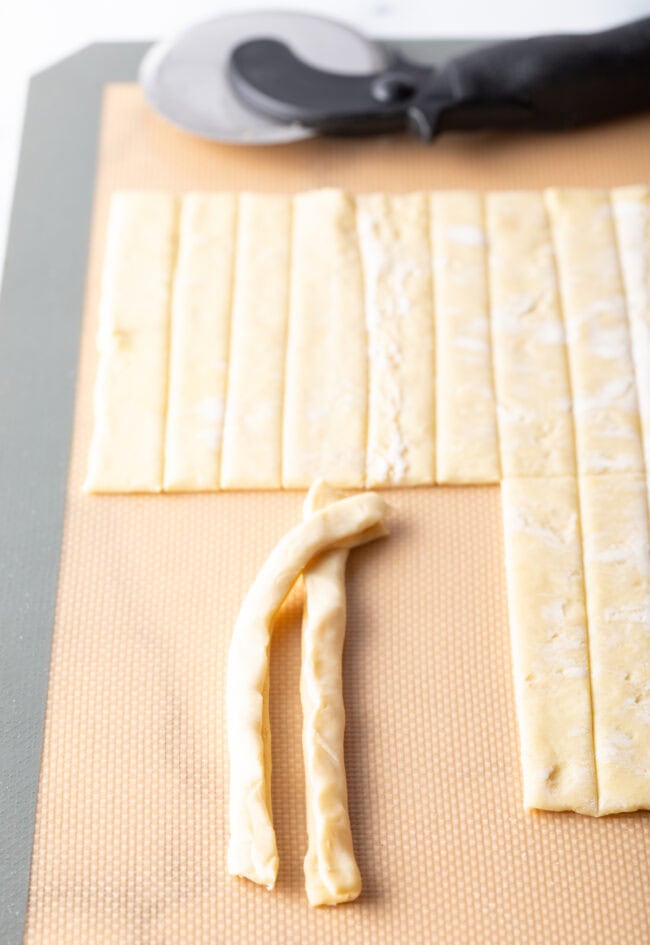 Tops of two strands of cut puff pastry sealed together.