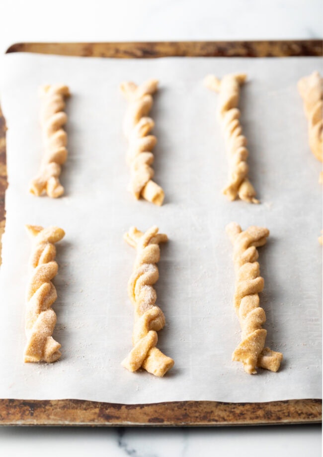 Unbaked twists on parchment on a baking sheet.