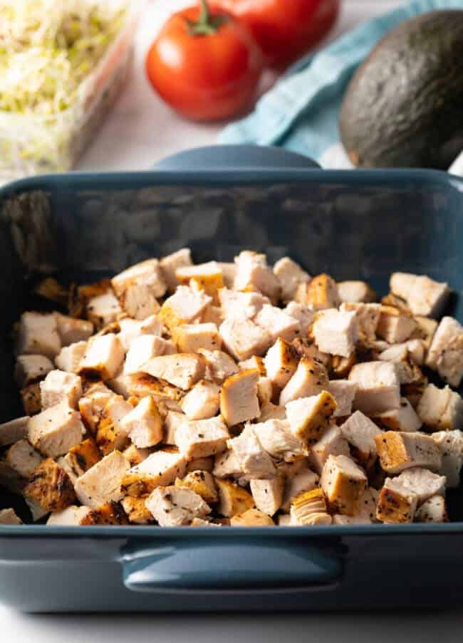 Pieces of grilled chicken in a blue square dish.