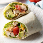 Top down view loaded chicken wrap, two pieces of the wrap are lying criss cross on each other.