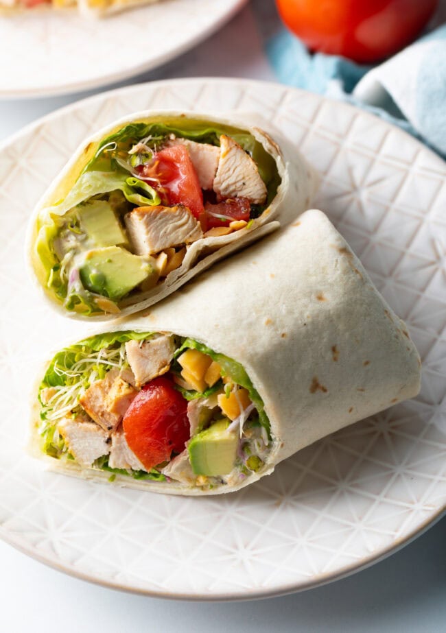 Top down view loaded chicken wrap, two pieces of the wrap are lying criss cross on each other.