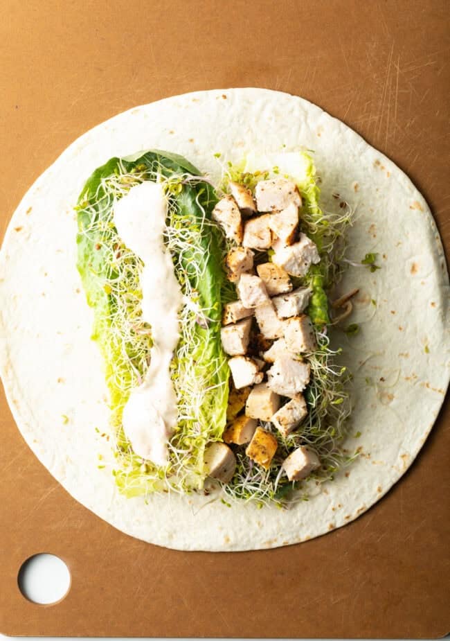 Tortilla flat and filled with chicken, lettuce and sprouts, dressing.