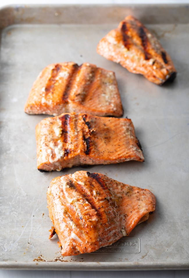 Salmon fillets grilled and cooling on a baking sheet.