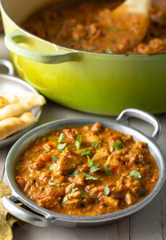 Easy Madras Chicken in a bowl next to a dutch oven full of curry.