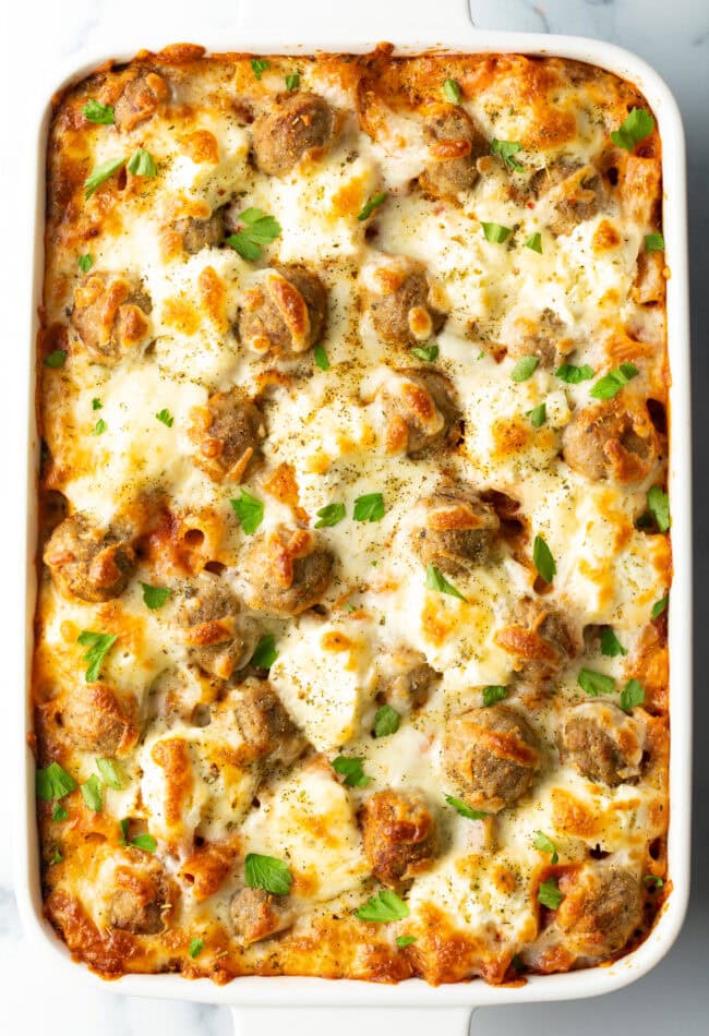 Baked meatball casserole in a white dish, bubbly cheese on top.