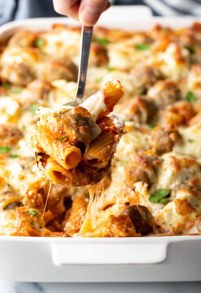 Metal spoon holding a serving of meatball casserole to camera.