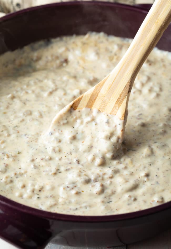 Easy sausage gravy in a pan with a wooden spoon.