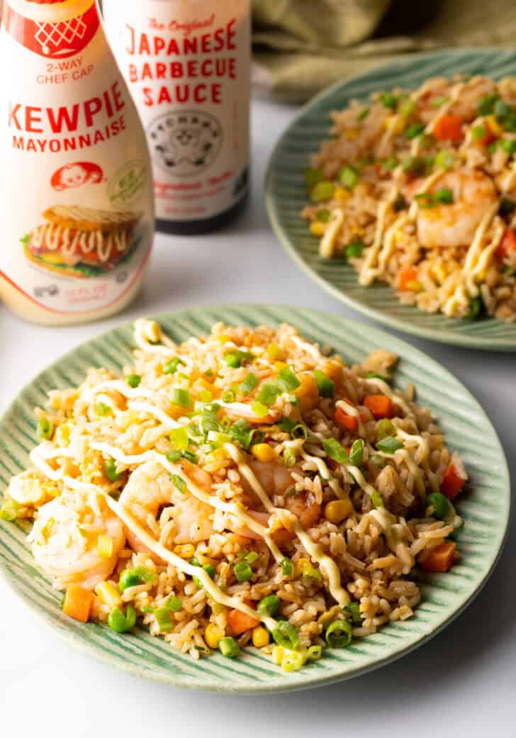 Green plate piled with shrimp fried rice, topped with a zig zag drizzle of yum yum sauce.