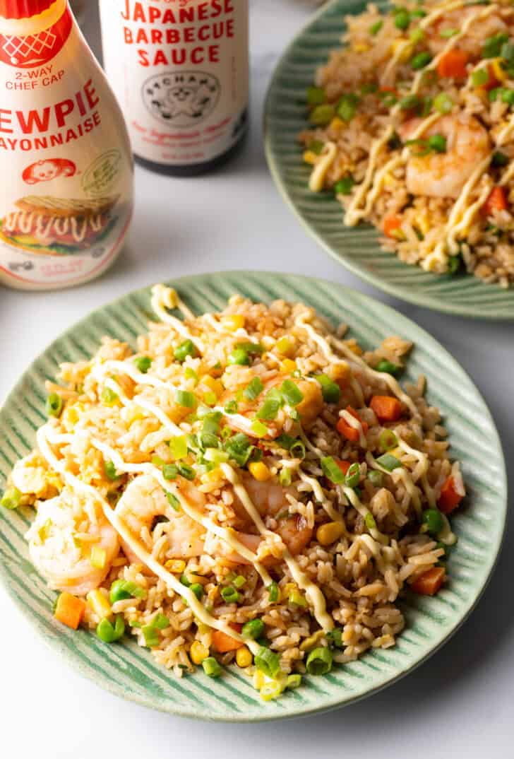 Green plate piled with shrimp fried rice, topped with a zig zag drizzle of yum yum sauce.