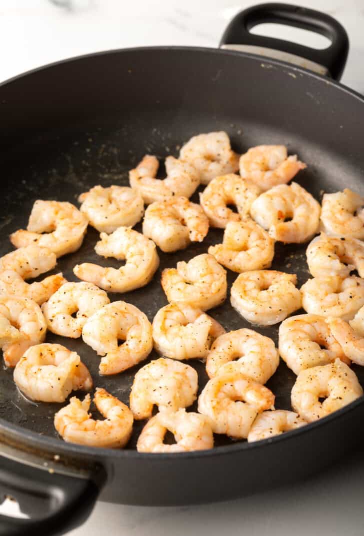 Cooking fresh raw shrimp in a skillet.