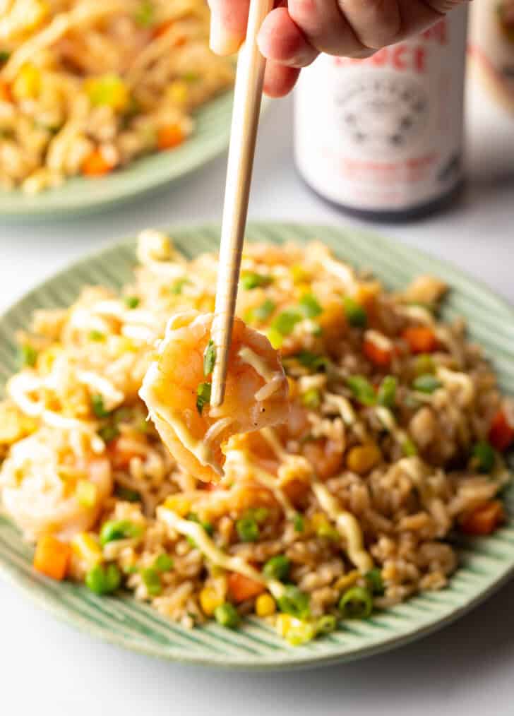 Chopsticks holding a cooked shrimp to camera.