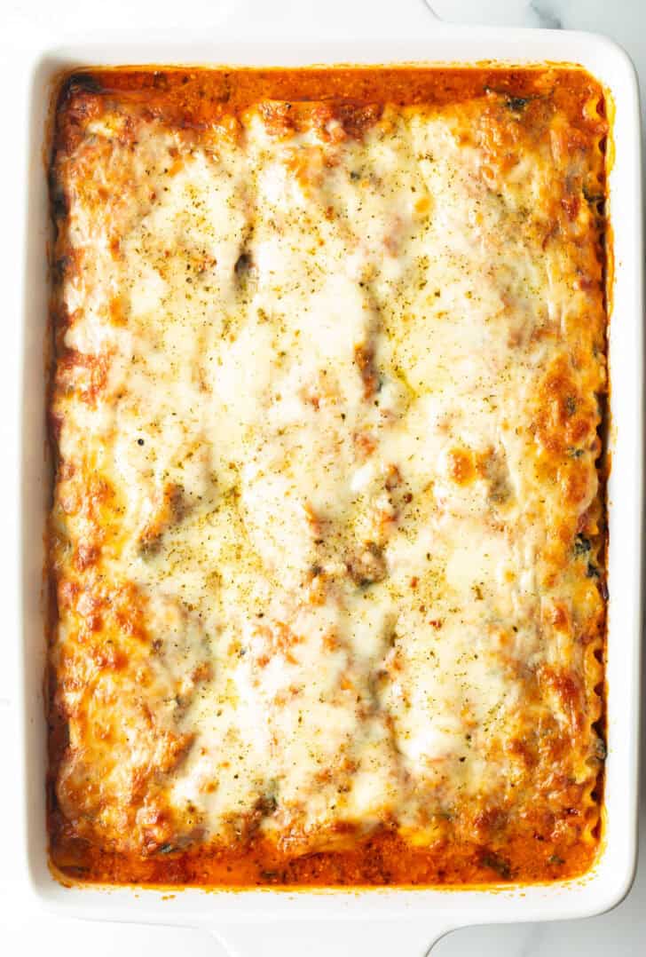 Baked vegetarian lasagna in a large white rectangle baking dish.