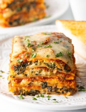 Square of cheesy spinach lasagna on a white plate.