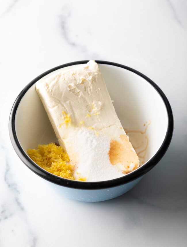 Block of cream cheese in a white bowl with lemon zest for cheese danish starbucks recipe