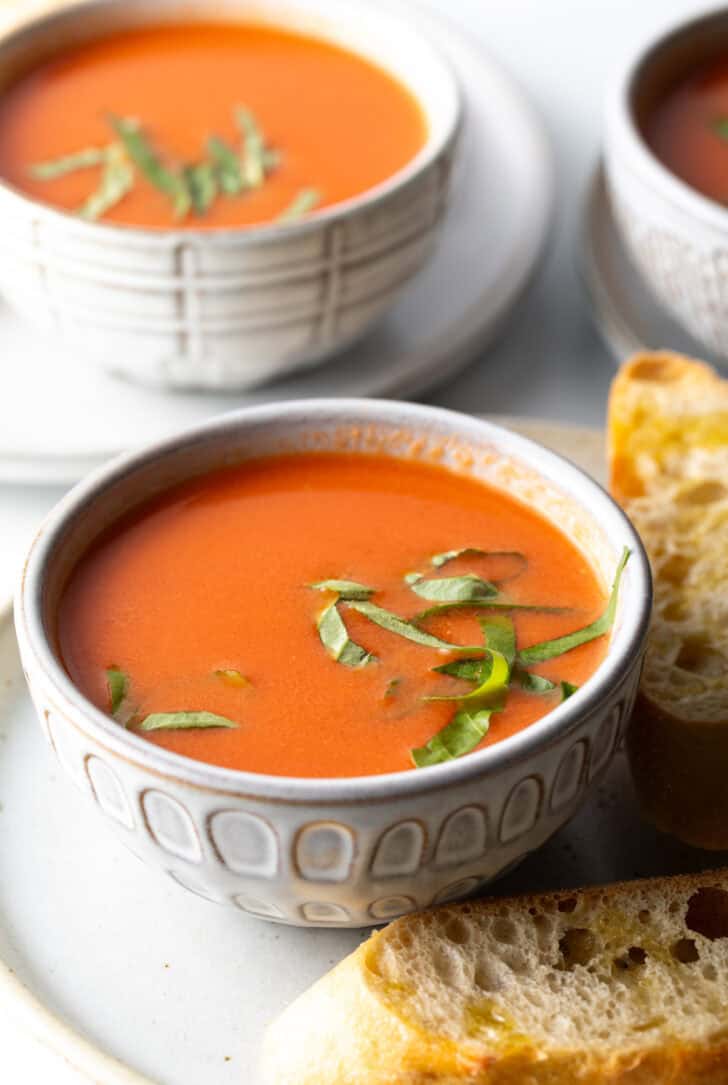 Bowl of tomato soup with slices of basil.