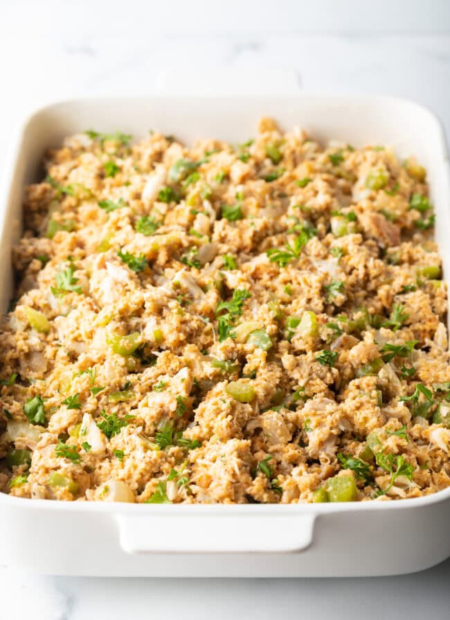 Unbaked seafood dressing in a white rectangle baking dish.