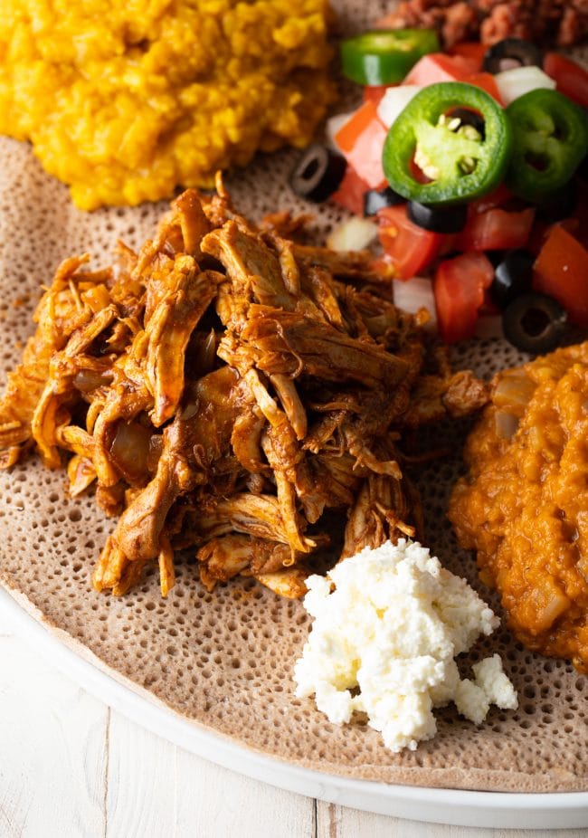 slow cooker chicken from Ethiopia on a plate with sides. 