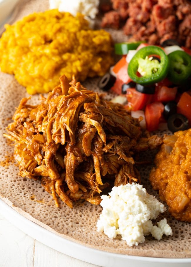 Chicken Doro Wat on a plate with salad and rice. 