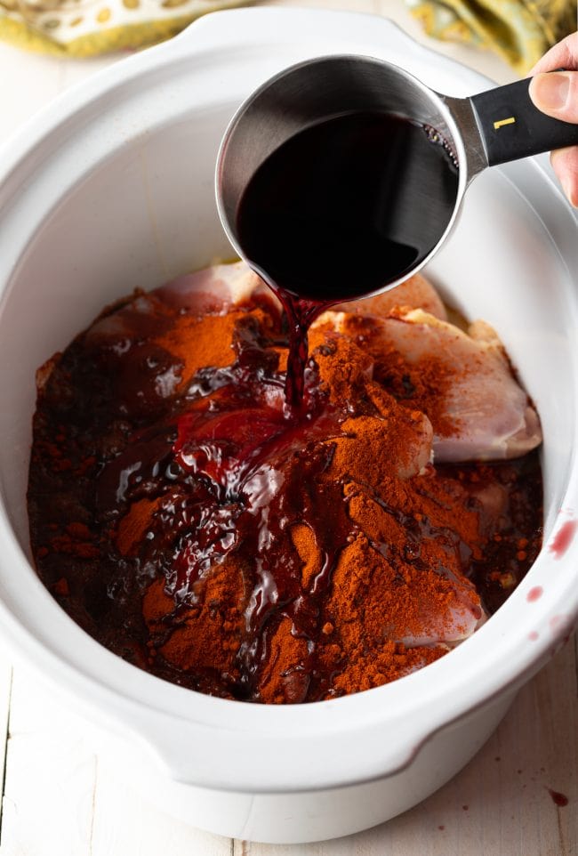 Doro Wat Ingredients being poured into a crockpot. 