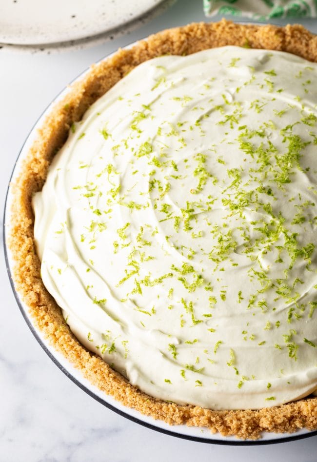 Full icebox pie with graham cracker crust and lime zest sprinkled on top.