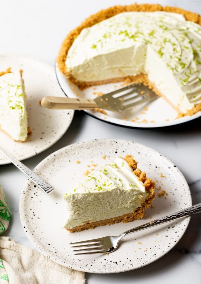 Slices of frozen key lime pie on plates with the full pie in the background