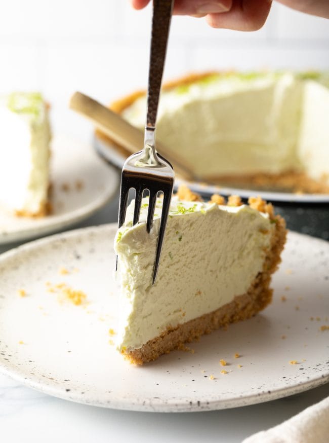 Slice of pie on a plate with a fork taking a bite out of it. 