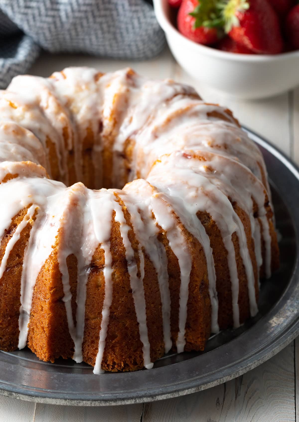 Strawberry bundt cake with a glaze on top on a serving platter. 