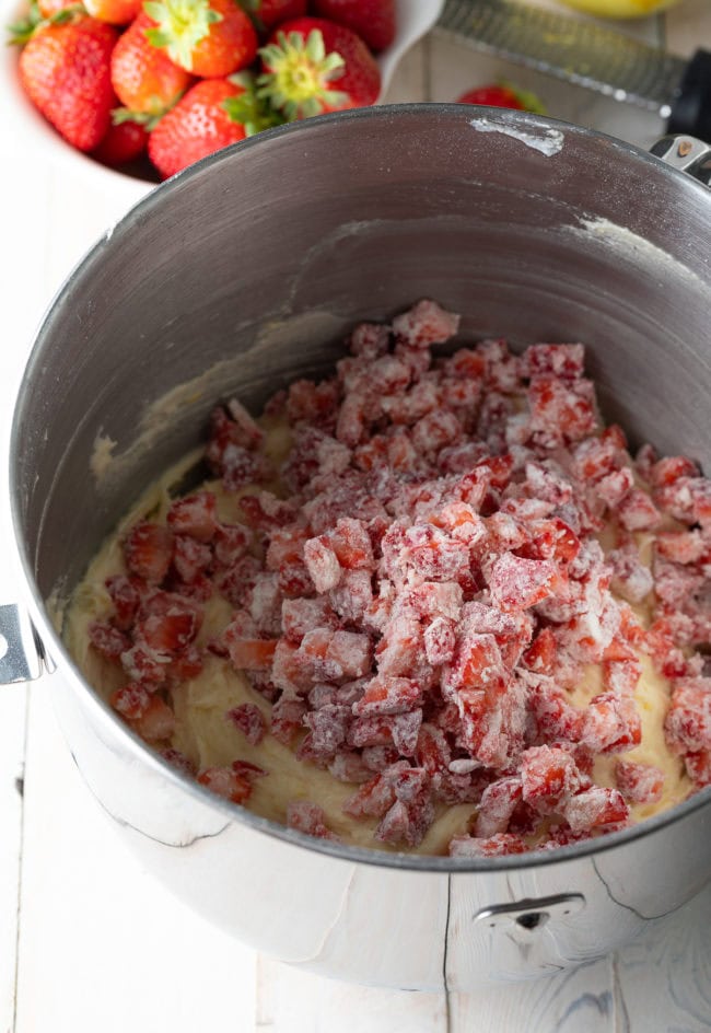 Strawberries added into the cake mix in a mixing bowl. 