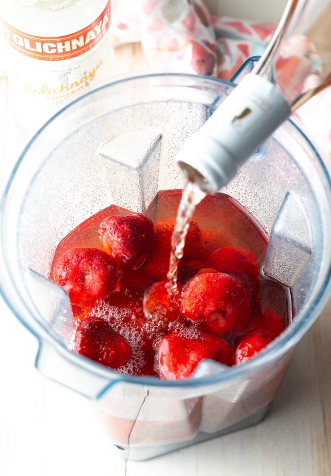 pouring in the blush wine over the strawberries in a blender