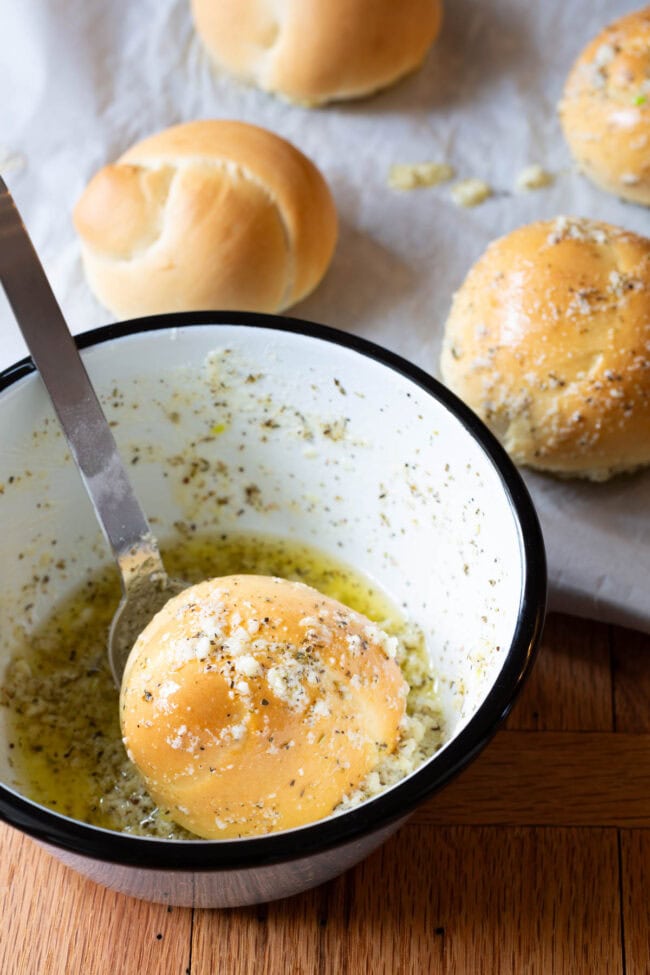 Dunking Baked Garlic Knots in garlic butter.