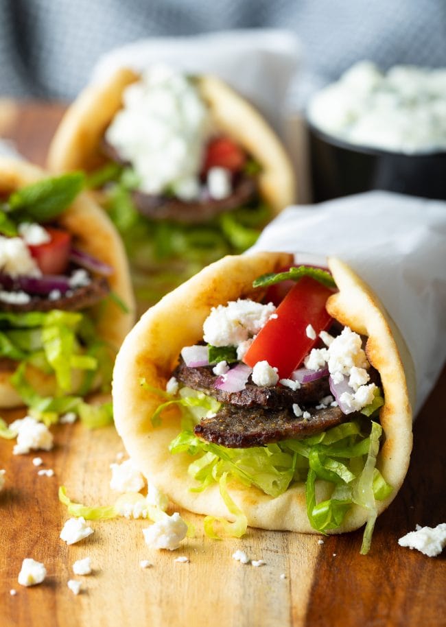 Three authentic greek lamb wraps on a wooden surface. 