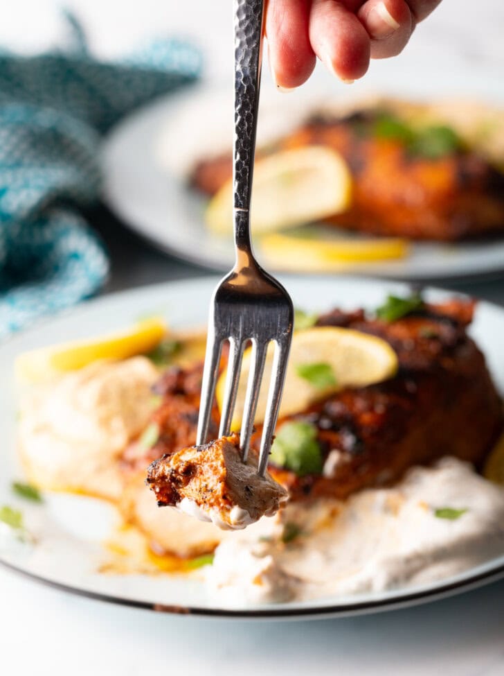 A fork holding a bite of chicken to camera.