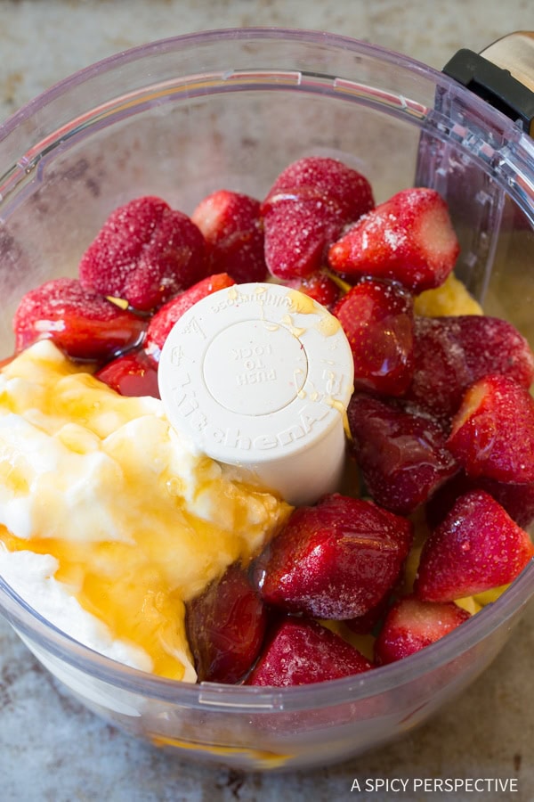 Ingredients for strawberry sherbet in a food processor bowl.