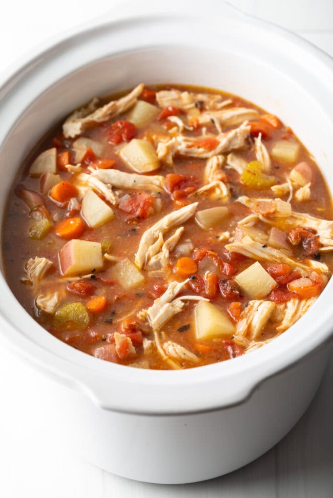 The stew all cooked and stirred together in a white crock pot.