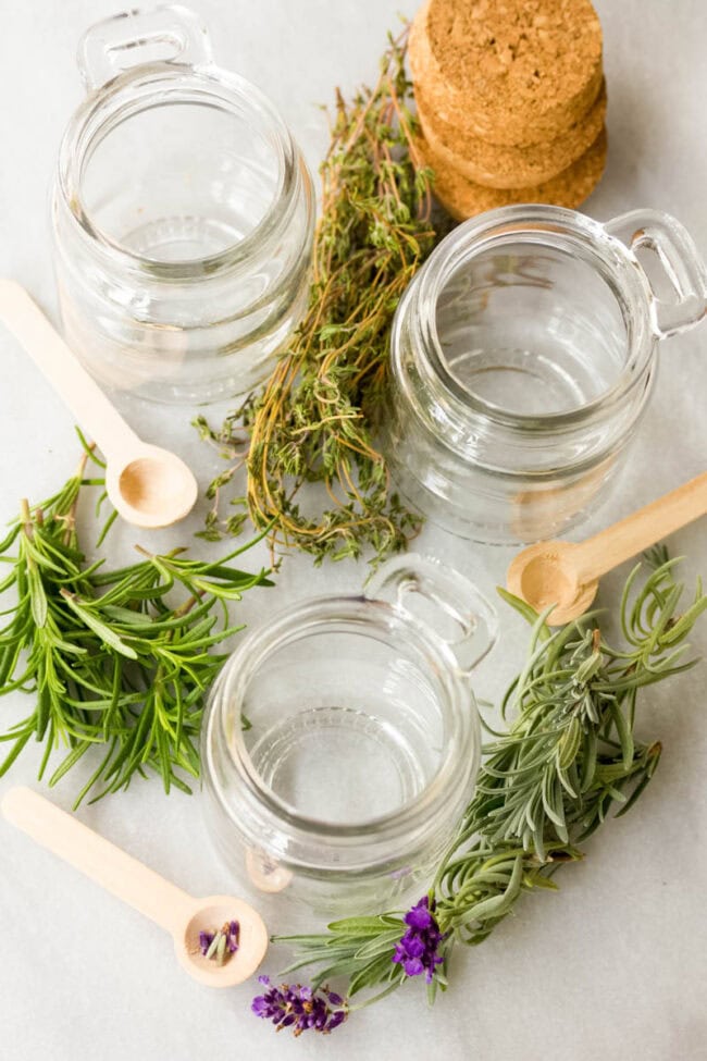 Infused Honey - Empty glass jars with fresh herbs placed around them. 