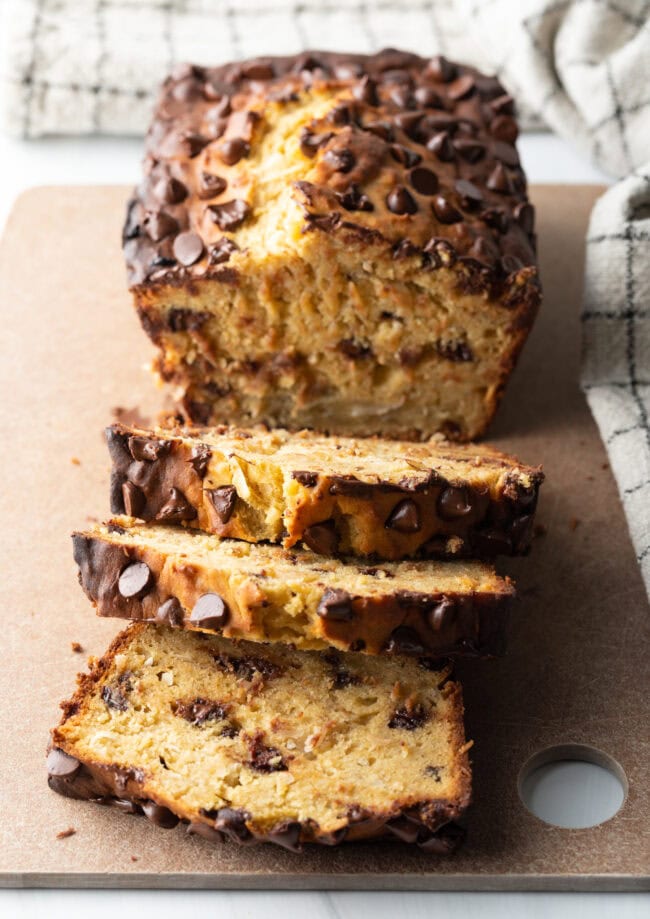 Loaf of high protein banana bread with chocolate chips. 3 slices are cut in front of the loaf.