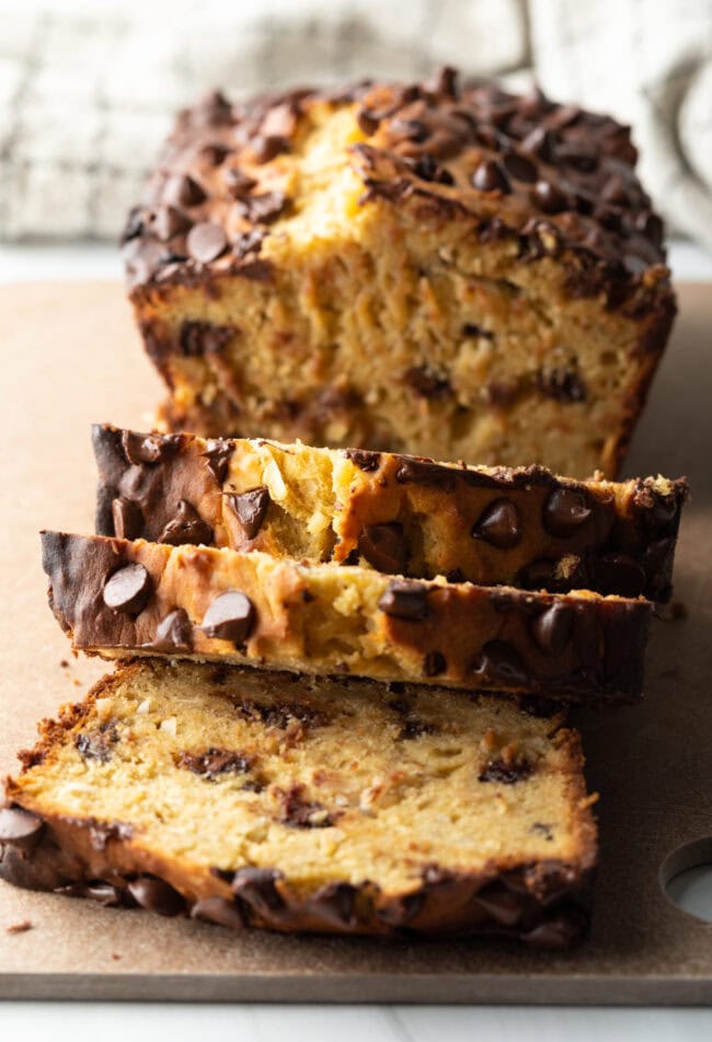 Loaf of high protein banana bread with chocolate chips. 3 slices are cut in front of the loaf.