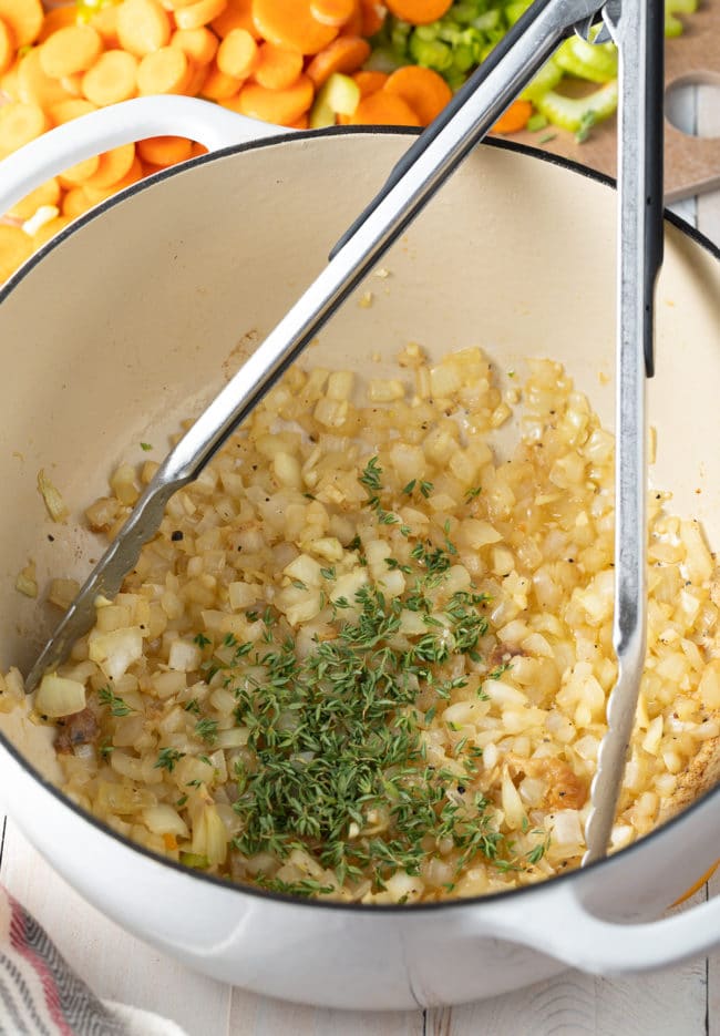 Onions, garlic and thyme cooking in a pot. 