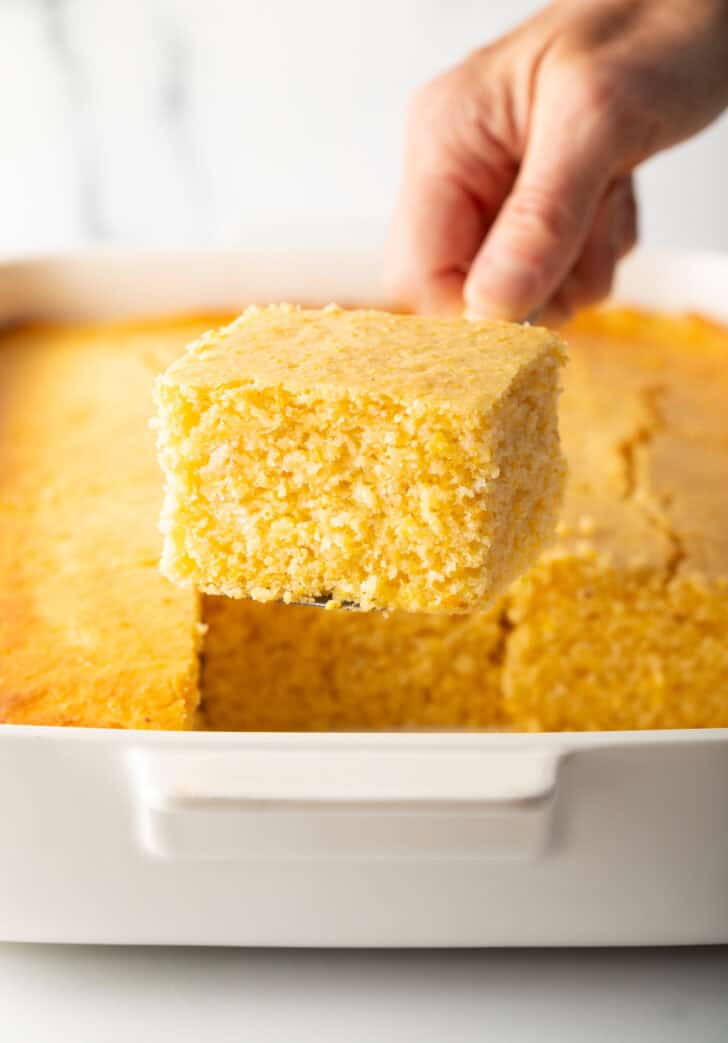 Hand holding a spatula with large square of sweet cornbread.