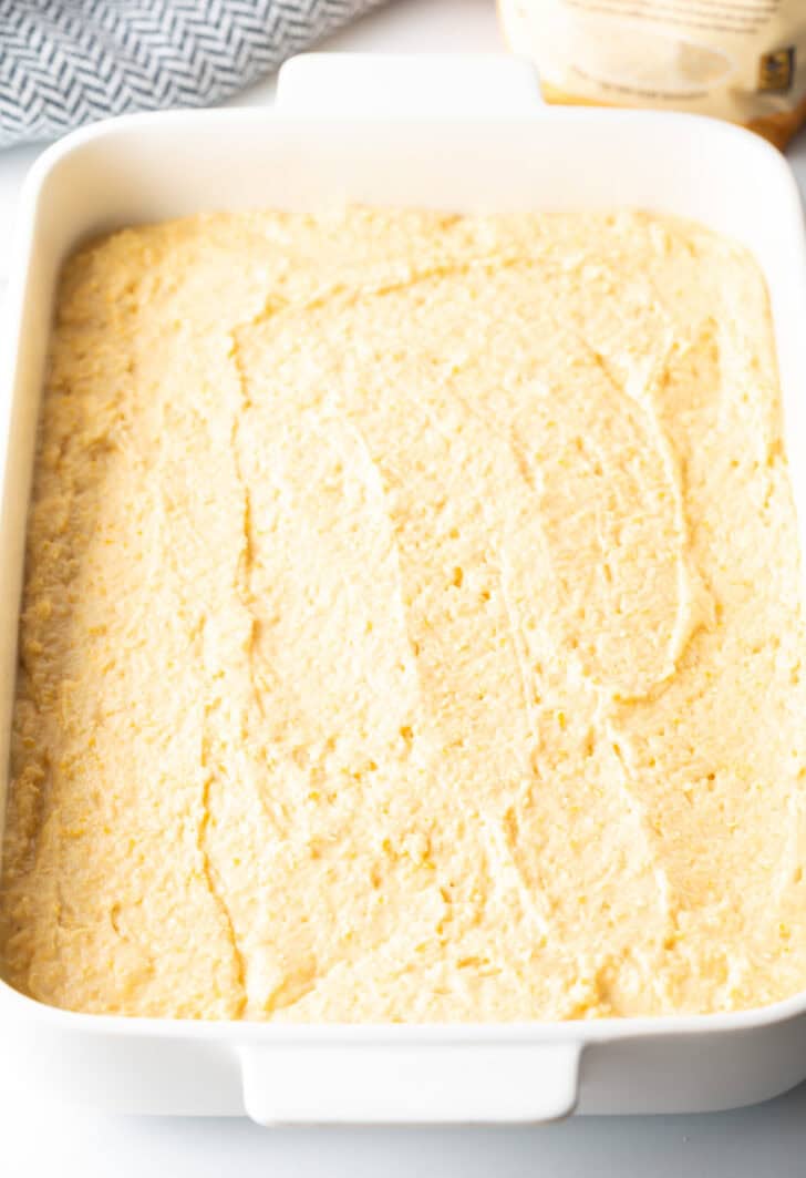 Raw batter spread into a large white baking dish.